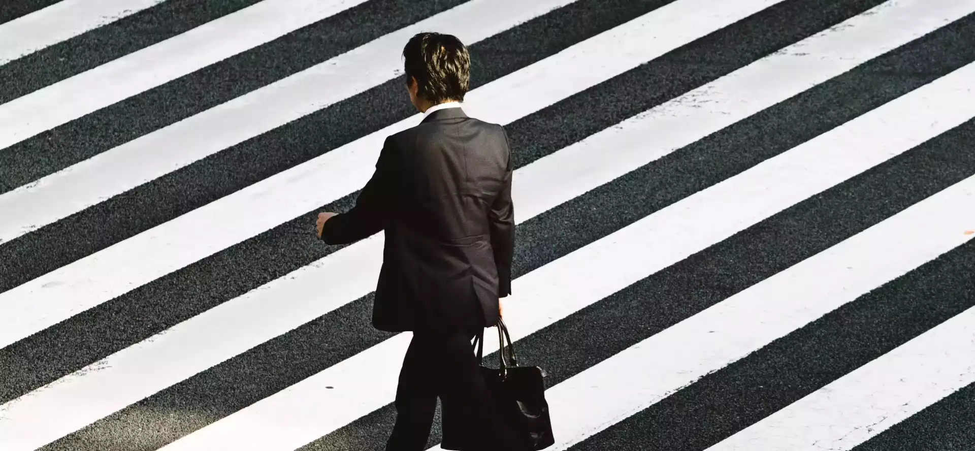 homme en costume traversant un passage piéton.